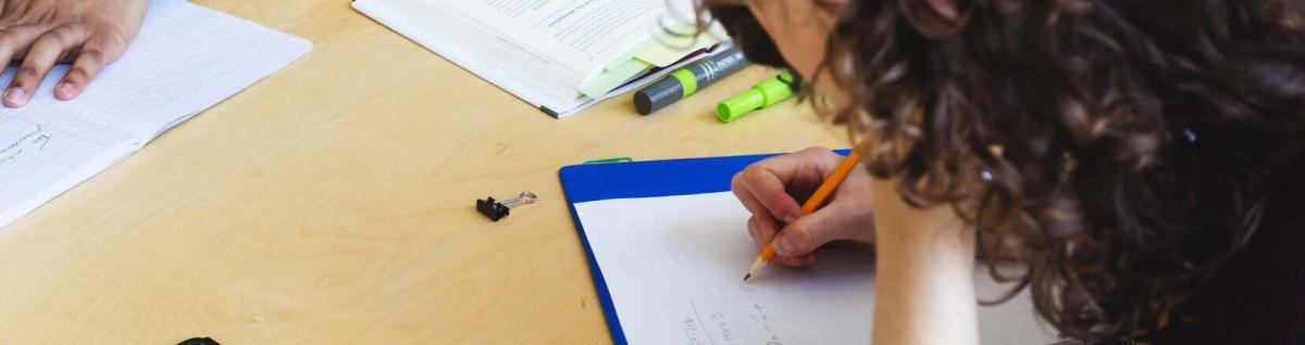 photo d'un étudiante qui écrit des notes dans son classeur