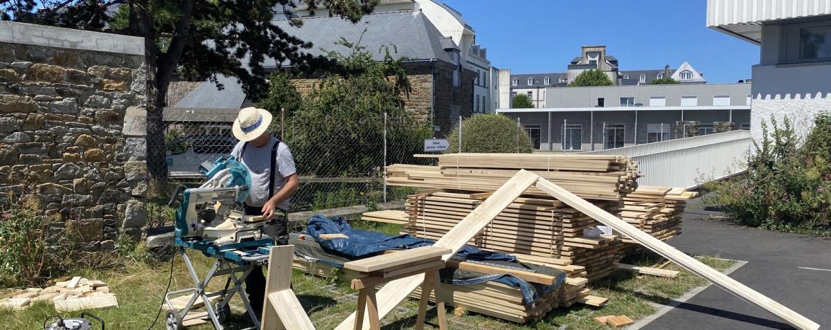 photo représentant un professionnel qui coupe du bois devant un tas de bois
