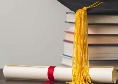 photo montrant une pile de livre, un diplôme et un chapeau de remise de diplôme